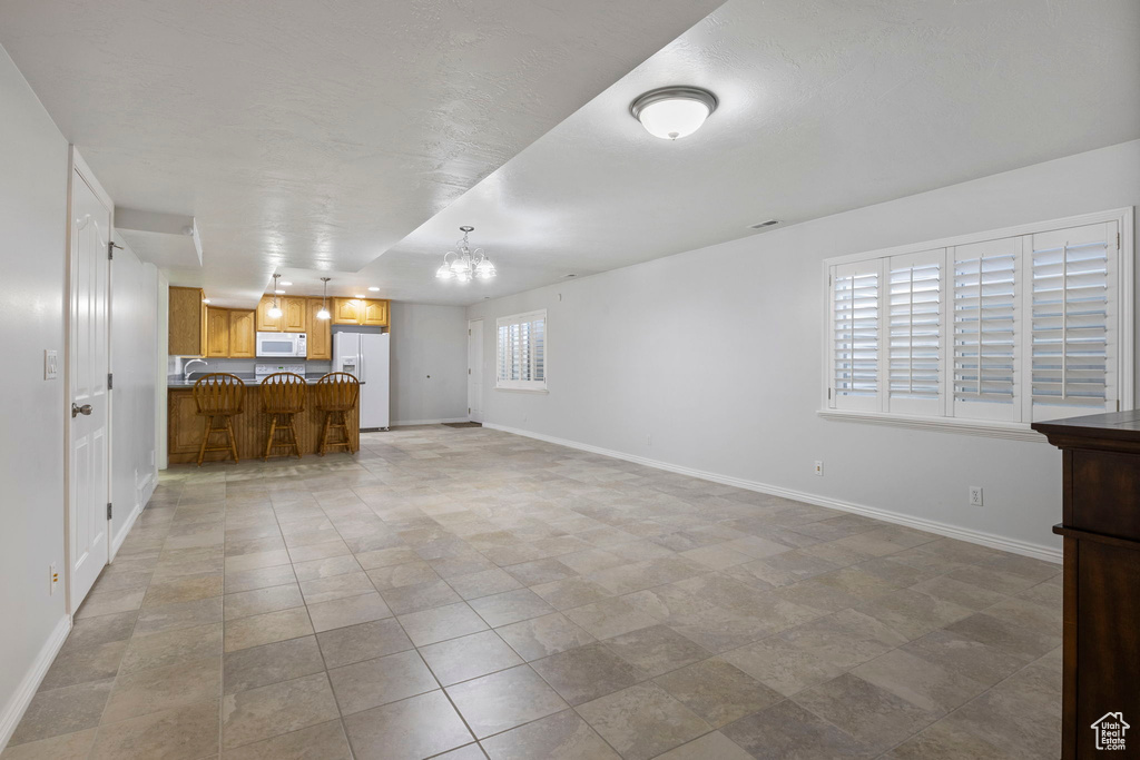 Unfurnished living room with a chandelier and light tile patterned flooring