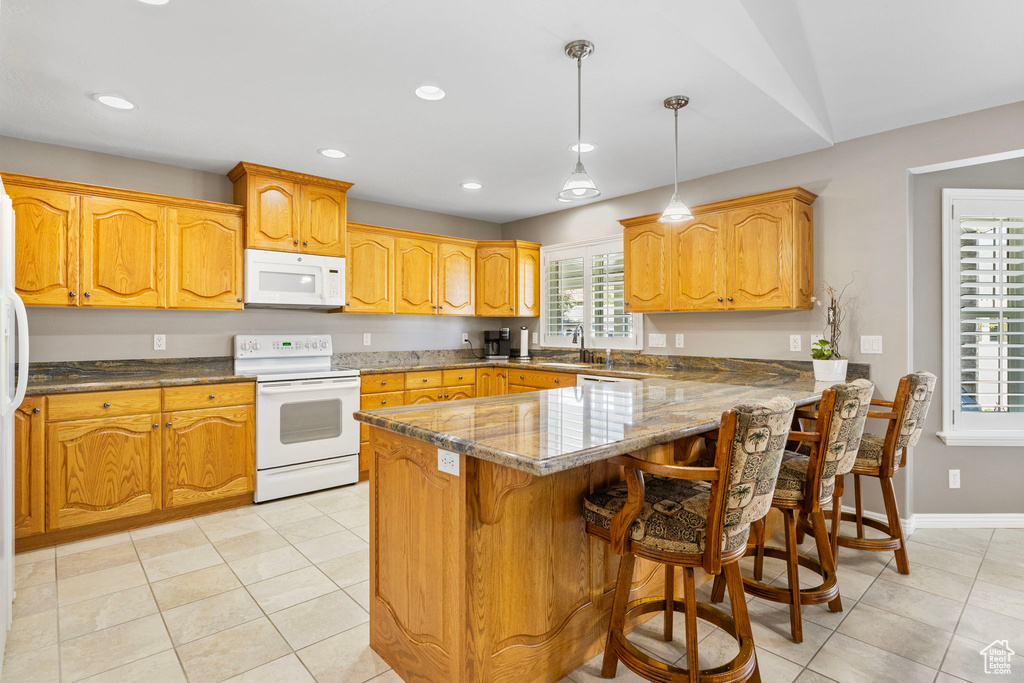 Kitchen with white appliances, pendant lighting, a breakfast bar, kitchen peninsula, and sink