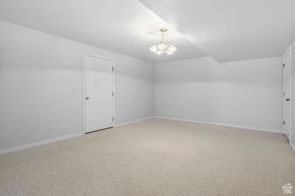 Unfurnished room with light colored carpet and a notable chandelier