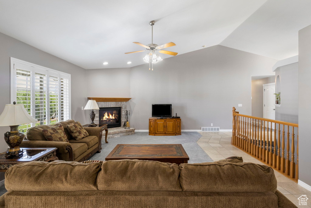 Living room featuring lofted ceiling, ceiling fan, and light tile patterned floors