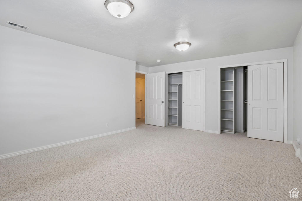 Unfurnished bedroom with carpet and two closets