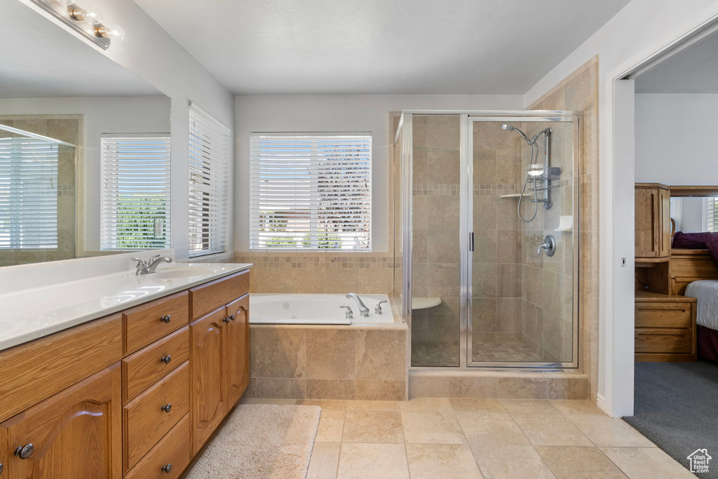 Bathroom featuring tile patterned flooring, vanity, and shower with separate bathtub