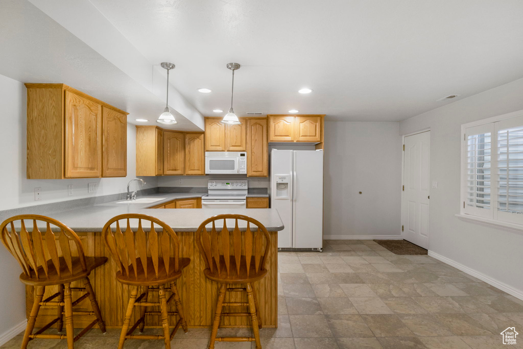 Kitchen featuring a breakfast bar, kitchen peninsula, sink, and white appliances