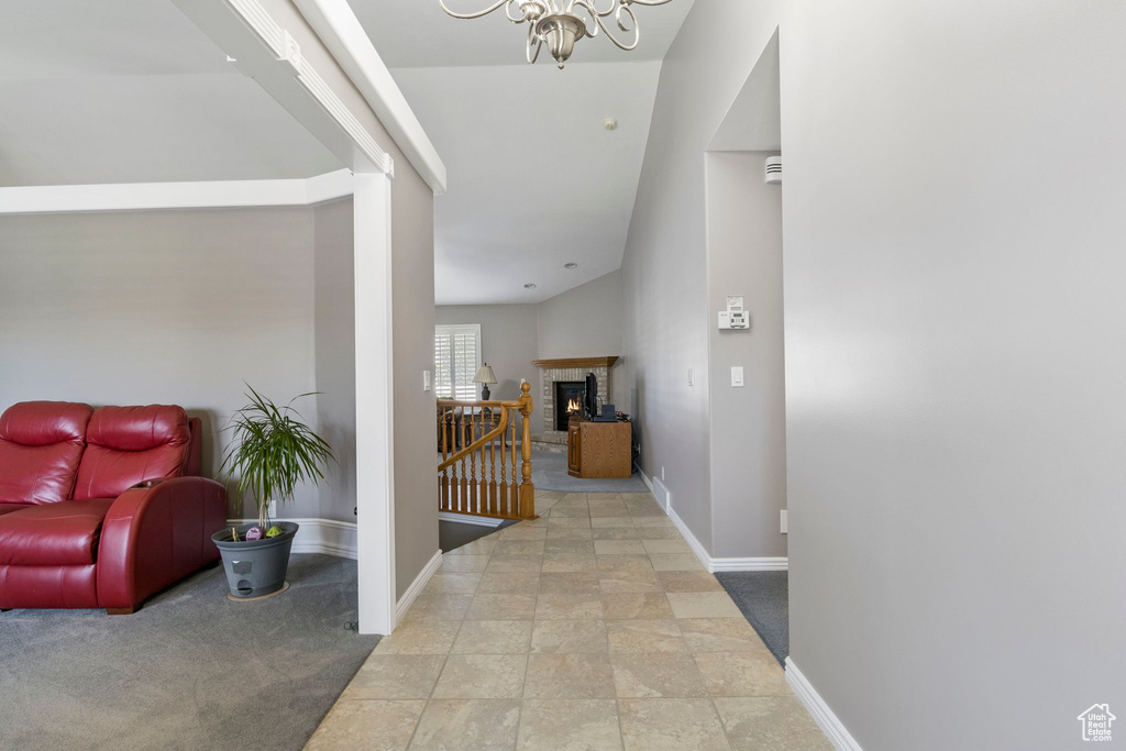 Corridor featuring lofted ceiling, carpet flooring, and an inviting chandelier