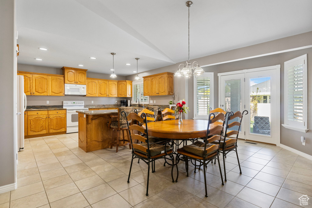 Tiled dining area with vaulted ceiling, a chandelier, and sink