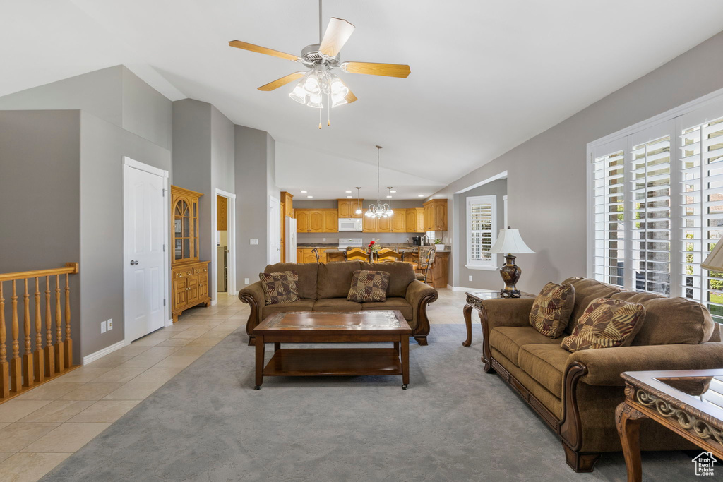 Tiled living room with high vaulted ceiling and ceiling fan with notable chandelier