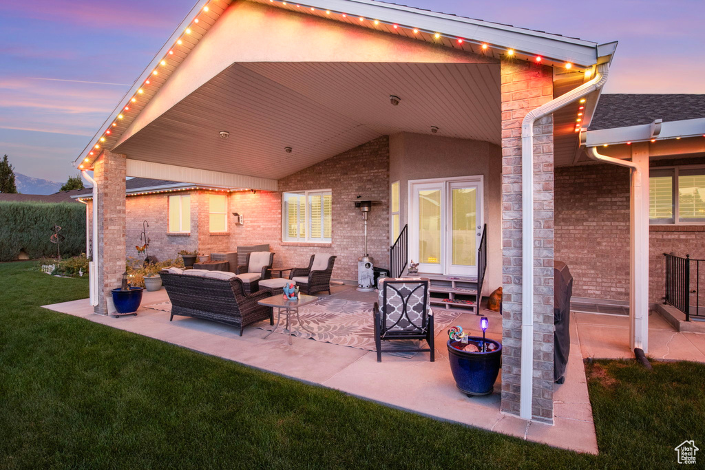 Patio terrace at dusk with a lawn and an outdoor living space