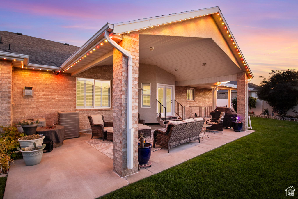 Back house at dusk featuring a lawn, a patio, and an outdoor hangout area