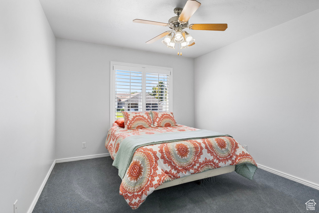 Bedroom with ceiling fan and dark colored carpet