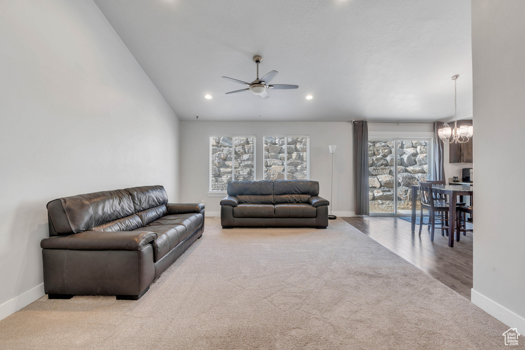 Carpeted living room featuring ceiling fan with notable chandelier