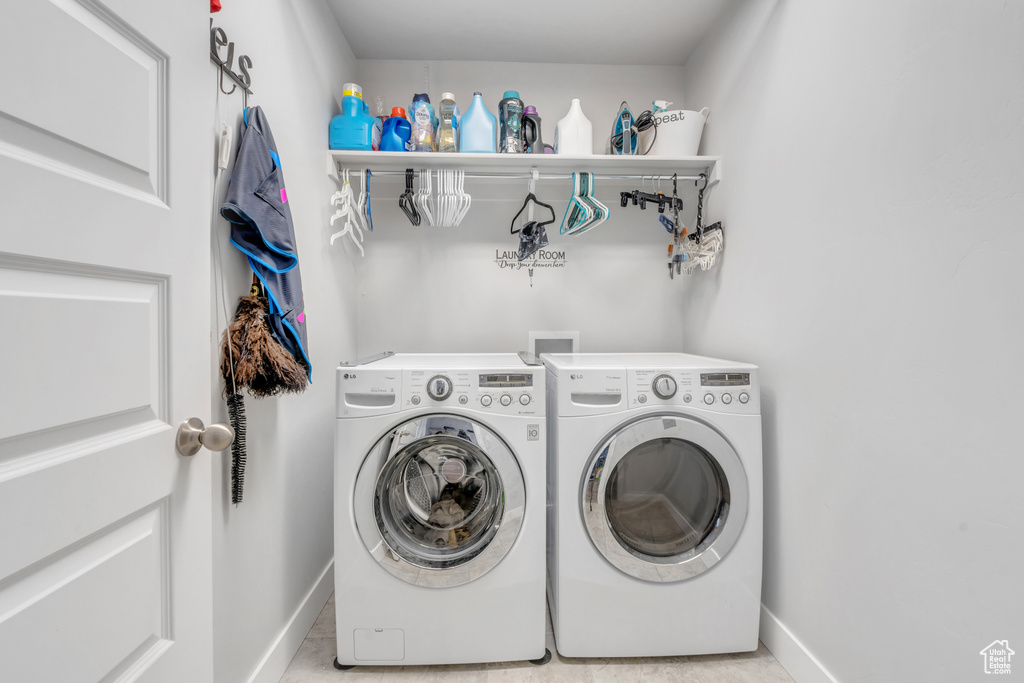 Laundry area featuring light tile patterned flooring and washer and clothes dryer