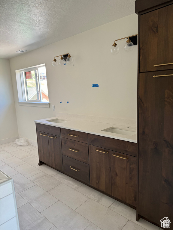 Bathroom featuring tile patterned floors, a textured ceiling, and vanity