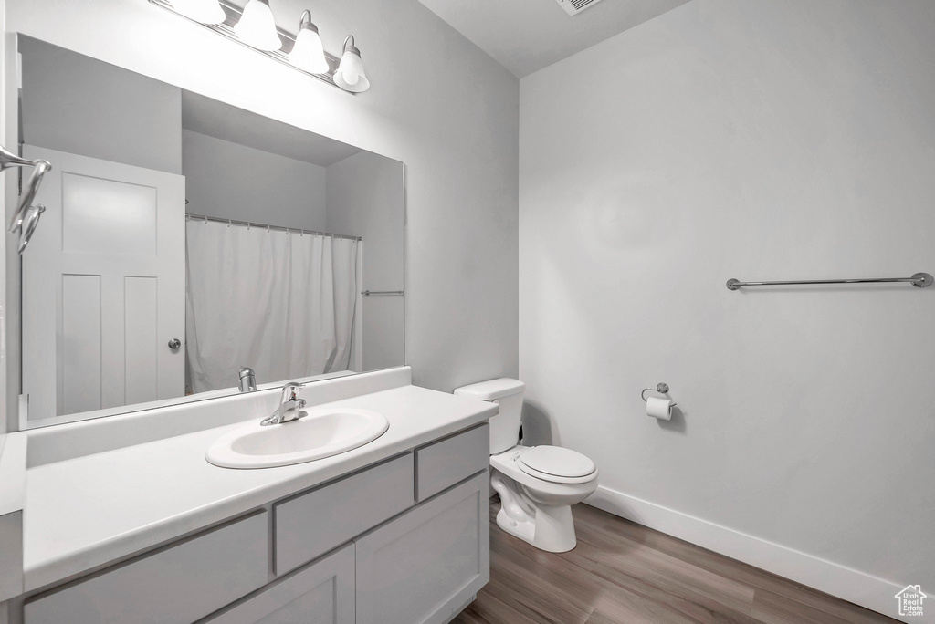 Bathroom featuring wood-type flooring, toilet, and vanity