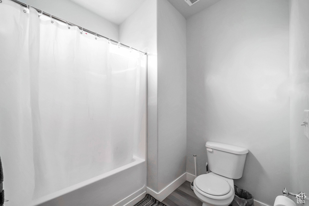 Bathroom featuring wood-type flooring, toilet, and shower / tub combo