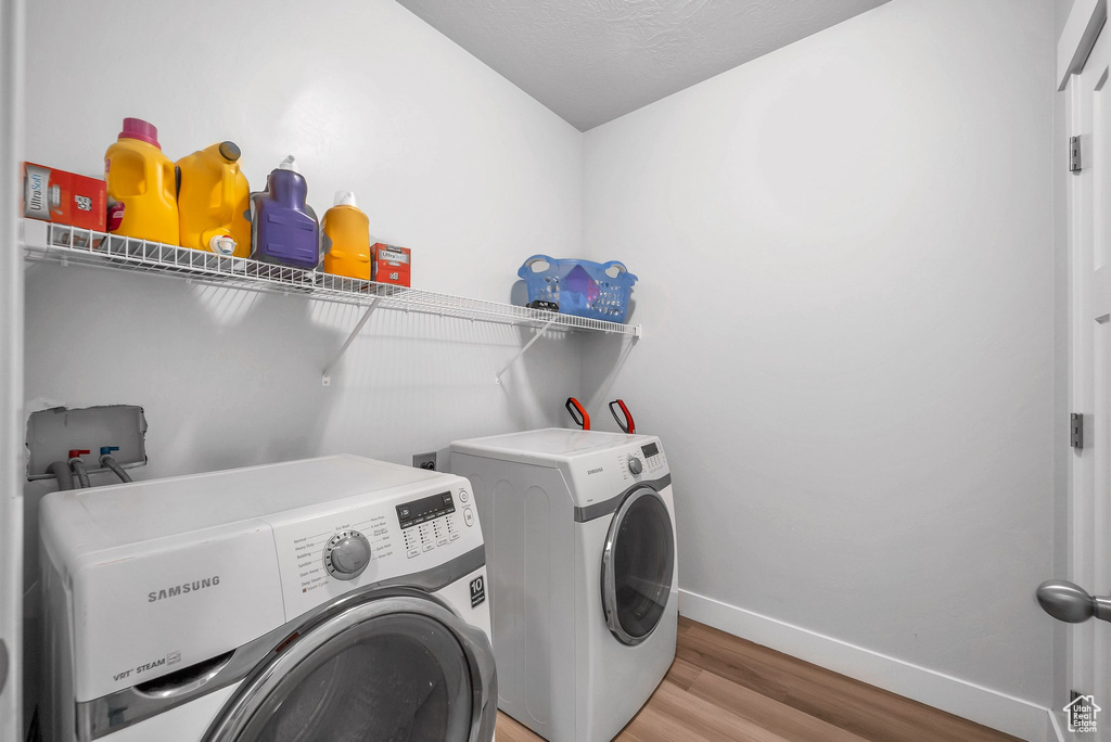 Laundry room with hardwood / wood-style floors, a textured ceiling, and washer and dryer