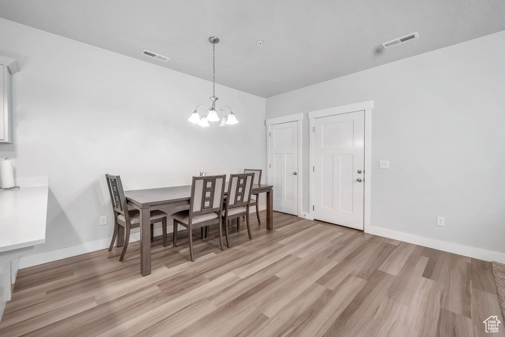 Dining area with light hardwood / wood-style flooring and a notable chandelier