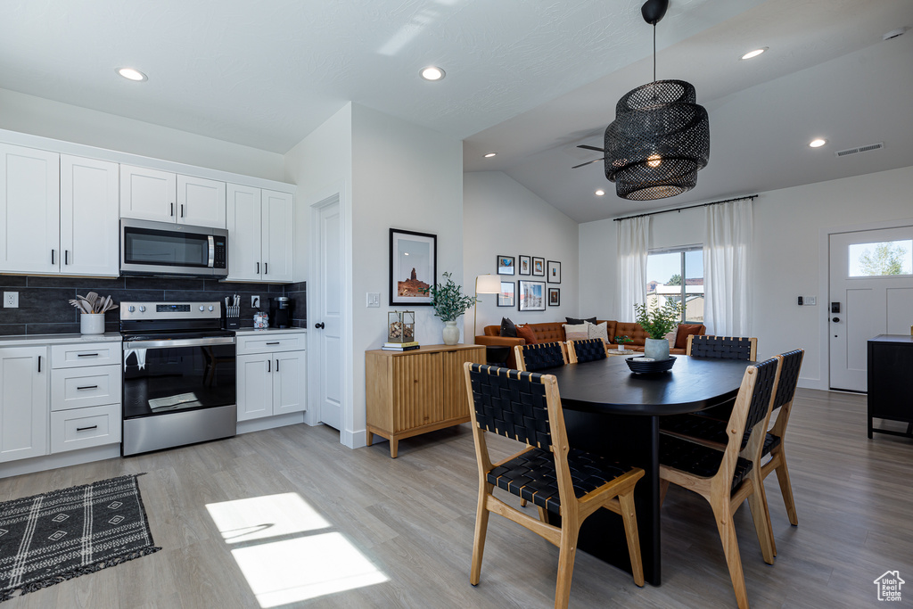 Dining space featuring lofted ceiling, plenty of natural light, and light hardwood / wood-style floors