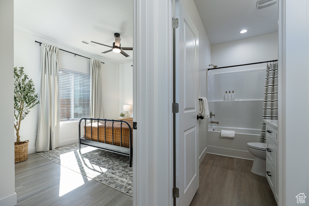 Full bathroom with toilet, vanity, wood-type flooring, ceiling fan, and shower / bath combination with curtain