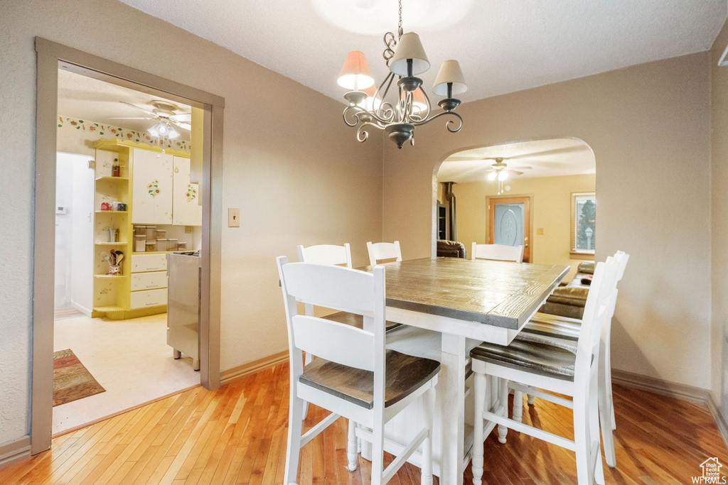 Dining area featuring ceiling fan with notable chandelier and light hardwood / wood-style floors