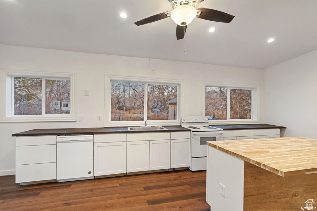 Kitchen with white appliances, dark hardwood / wood-style flooring, ceiling fan, sink, and wooden counters