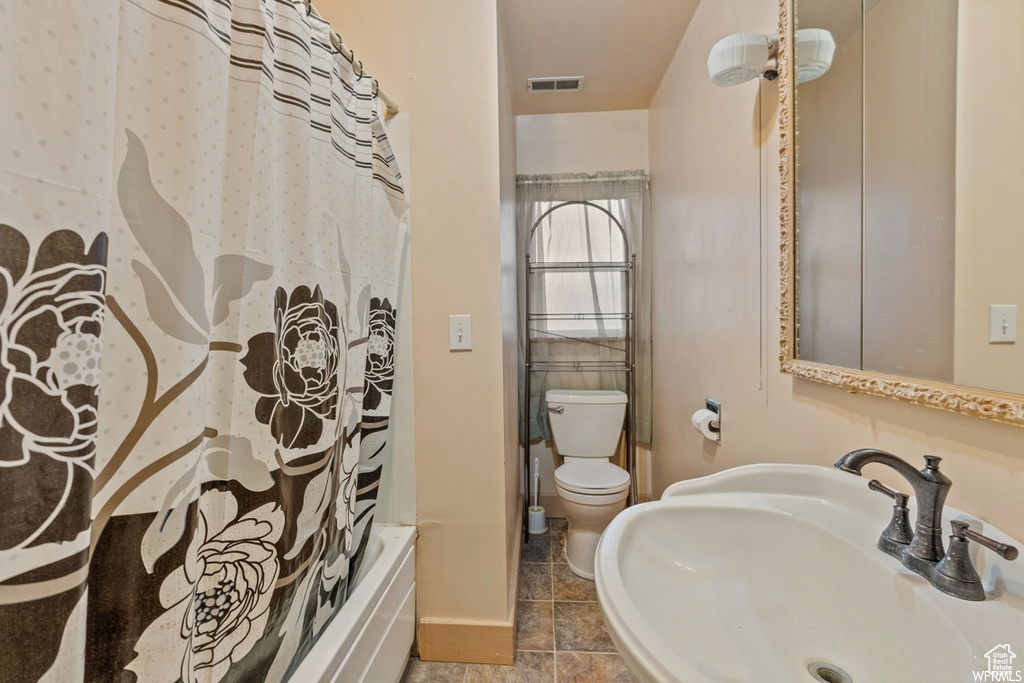 Full bathroom with toilet, shower / bath combination with curtain, sink, and tile patterned flooring