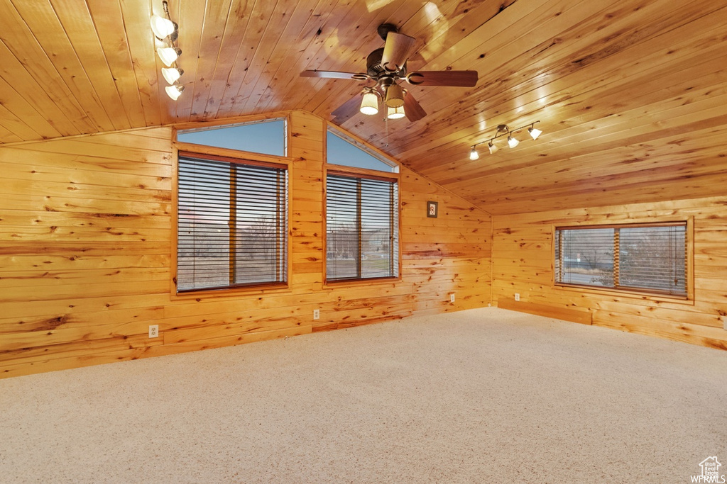 Interior space with wooden ceiling, carpet flooring, lofted ceiling, wood walls, and ceiling fan