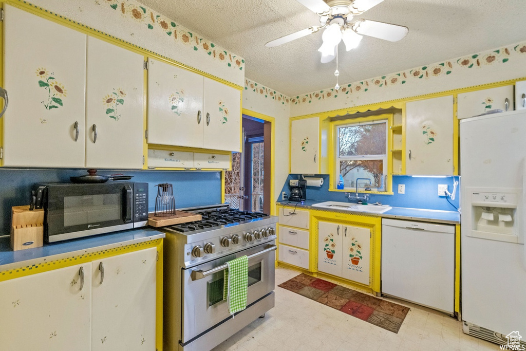 Kitchen with a textured ceiling, stainless steel appliances, sink, ceiling fan, and white cabinets