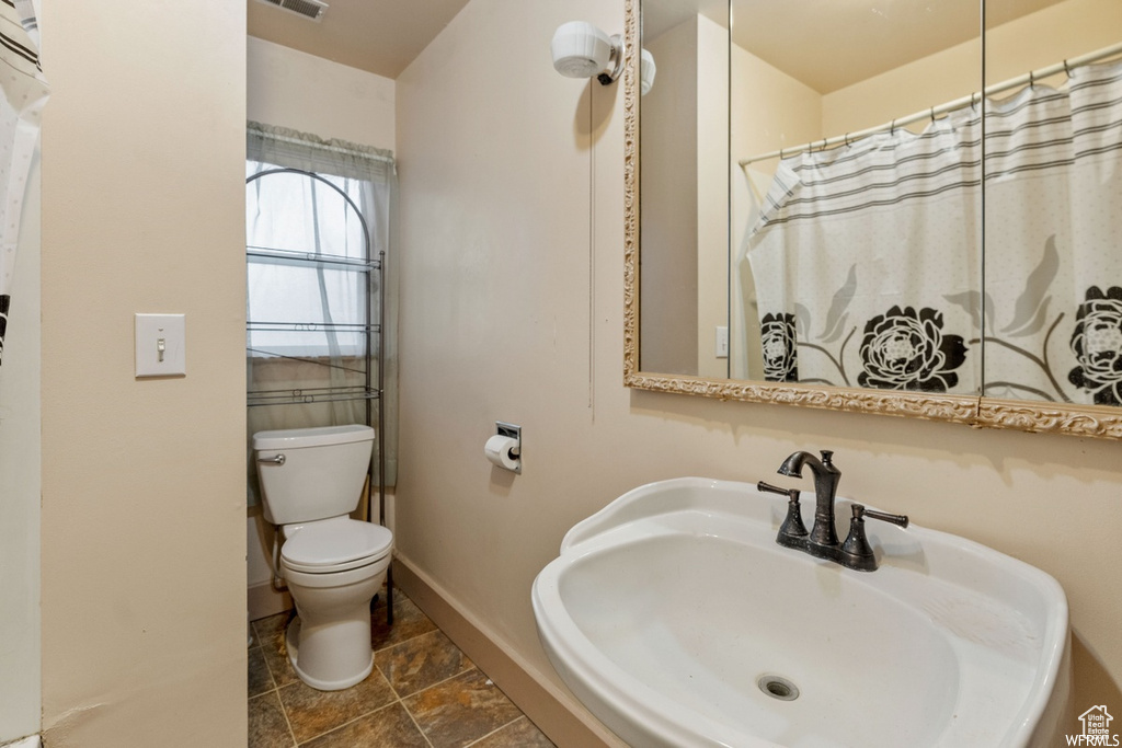 Bathroom featuring a shower with shower curtain, toilet, and sink