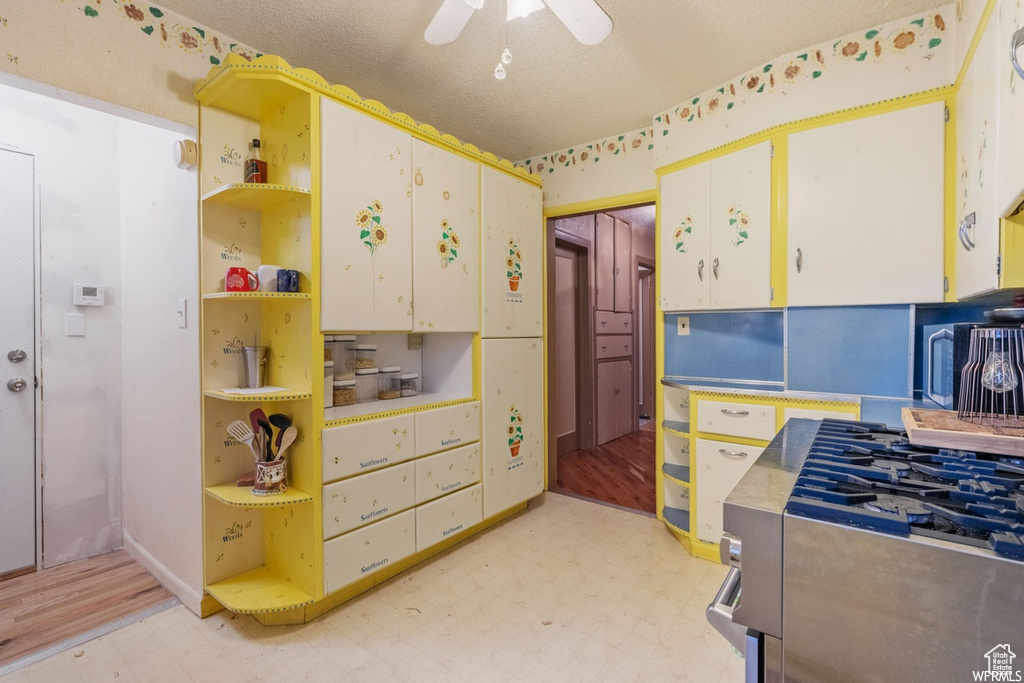 Kitchen featuring ceiling fan, light hardwood / wood-style floors, white cabinetry, and a textured ceiling