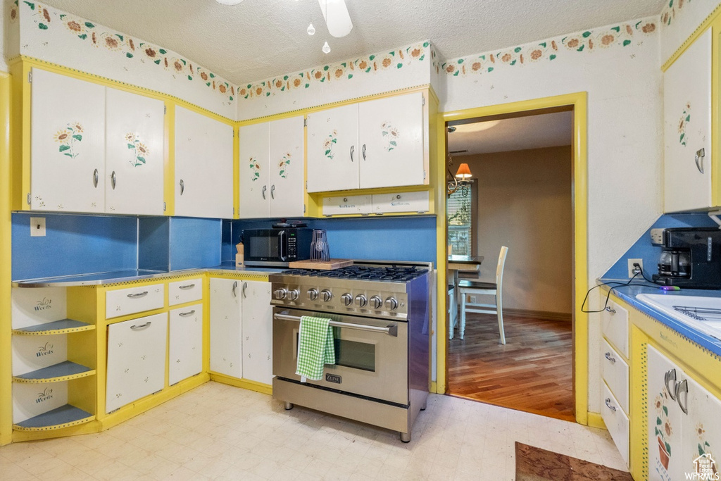 Kitchen featuring white cabinets, light hardwood / wood-style floors, high end stove, and a textured ceiling