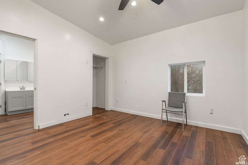 Unfurnished bedroom with hardwood / wood-style floors, connected bathroom, sink, ceiling fan, and lofted ceiling