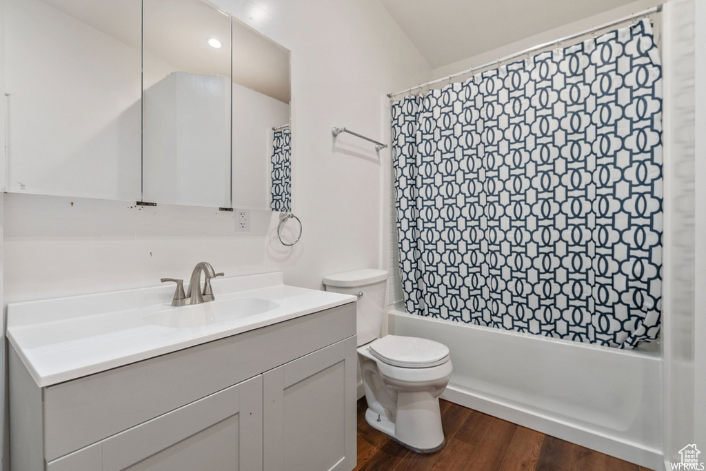 Full bathroom featuring shower / bath combo with shower curtain, wood-type flooring, toilet, and vanity