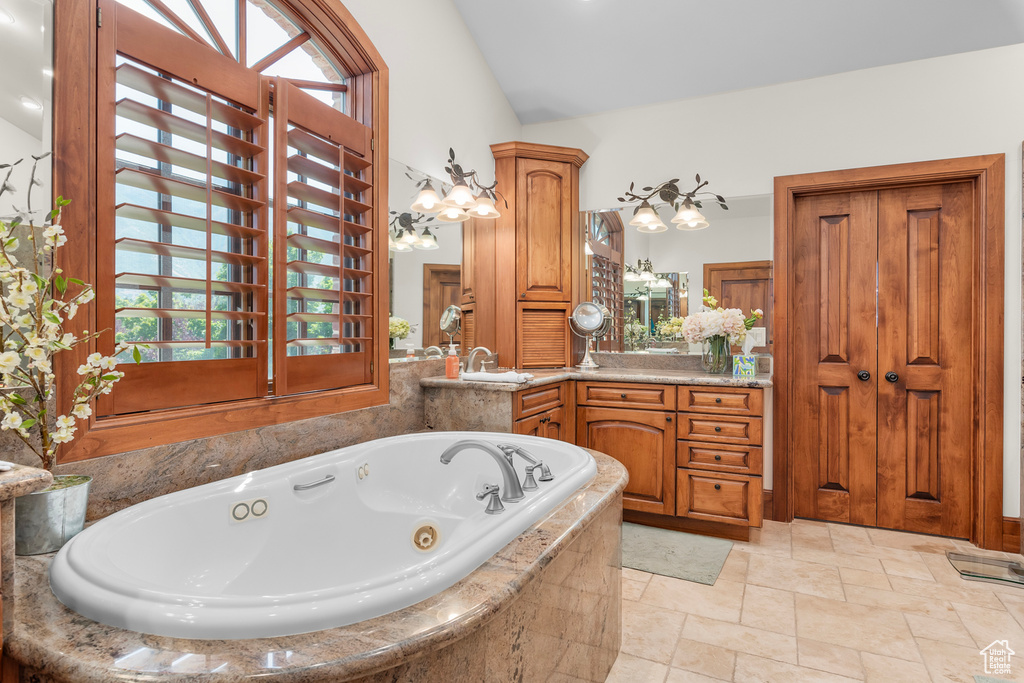 Bathroom featuring a relaxing tiled tub, a chandelier, and vanity