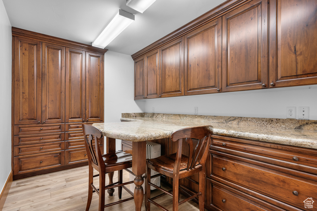 Kitchen featuring a kitchen bar, light stone counters, and light wood-type flooring