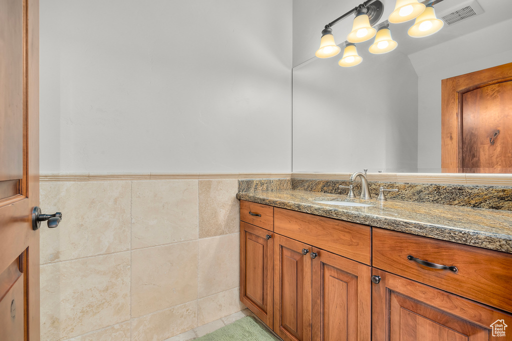 Bathroom with tile patterned floors, tile walls, and vanity