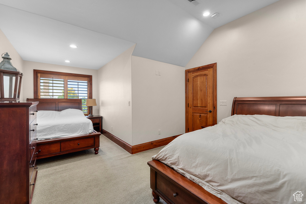 Bedroom featuring light carpet and vaulted ceiling