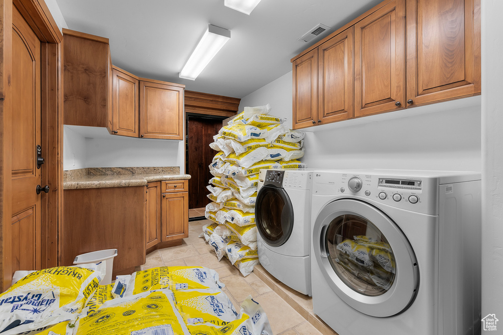 Laundry area featuring independent washer and dryer, cabinets, and light tile patterned flooring