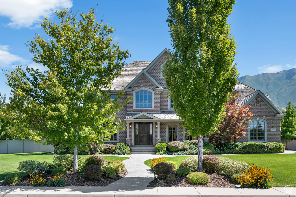 Obstructed view of property featuring a mountain view and a front lawn