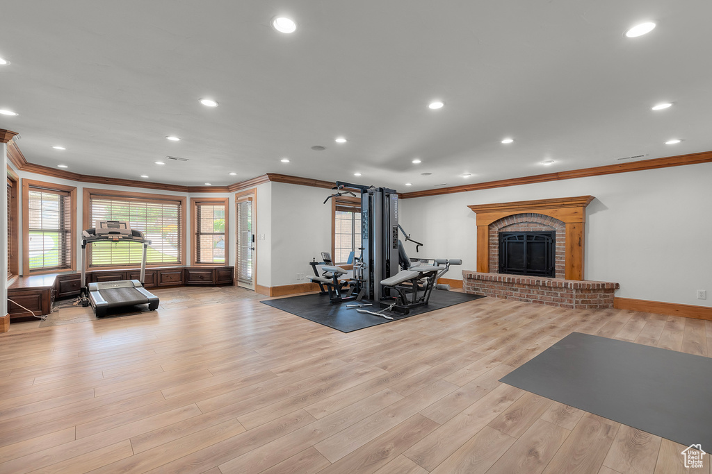 Exercise room featuring ornamental molding, a brick fireplace, and light hardwood / wood-style floors