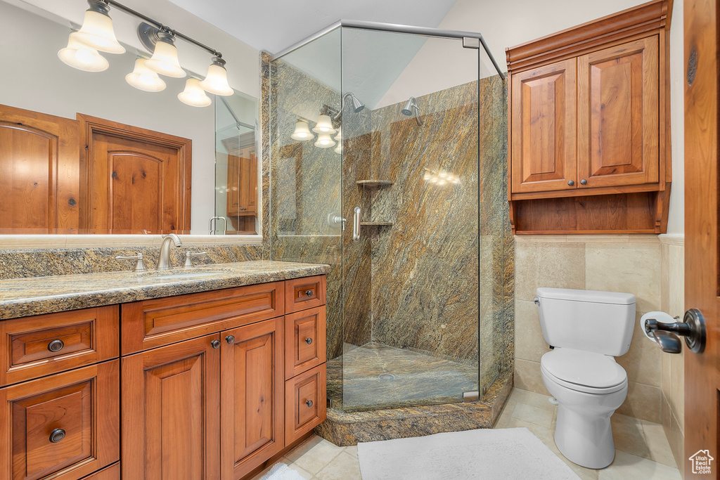 Bathroom with vanity, walk in shower, tile patterned flooring, tile walls, and toilet