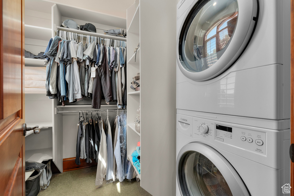 Clothes washing area with stacked washer / dryer and light carpet