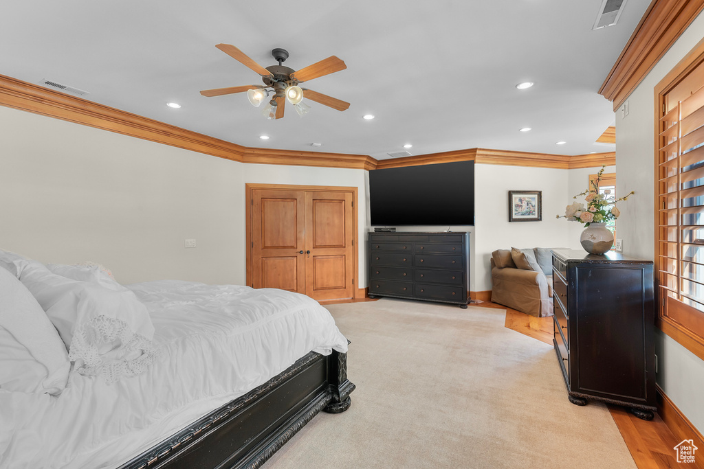 Carpeted bedroom with ceiling fan and crown molding