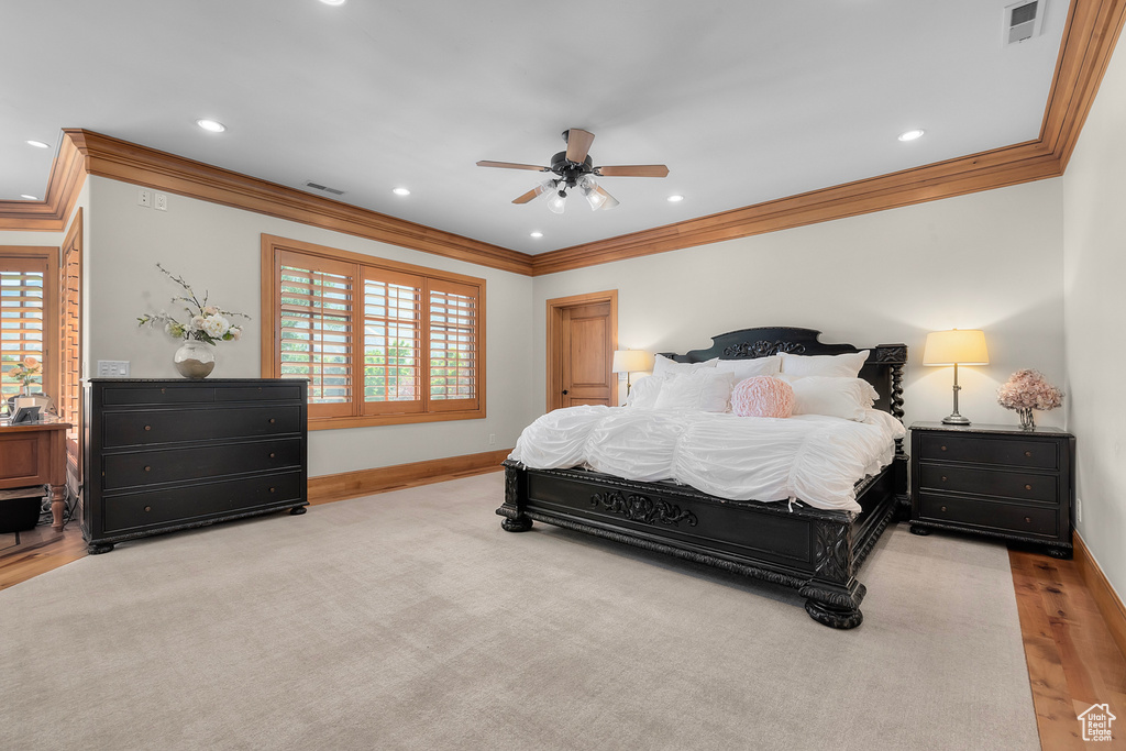 Bedroom with ceiling fan, ornamental molding, and light wood-type flooring