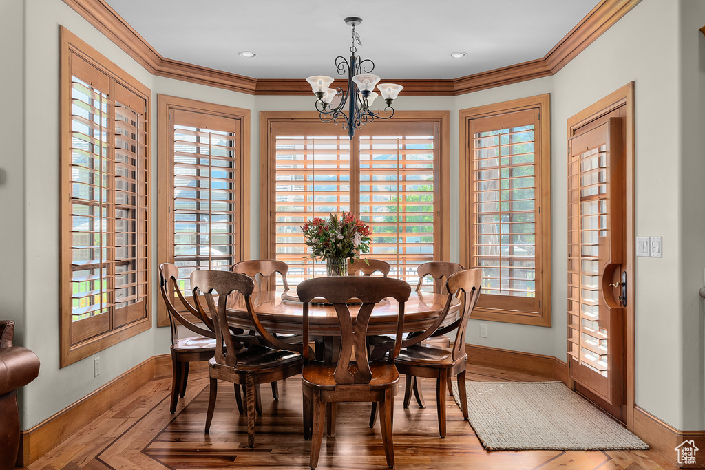 Dining space with hardwood / wood-style flooring, a notable chandelier, and ornamental molding