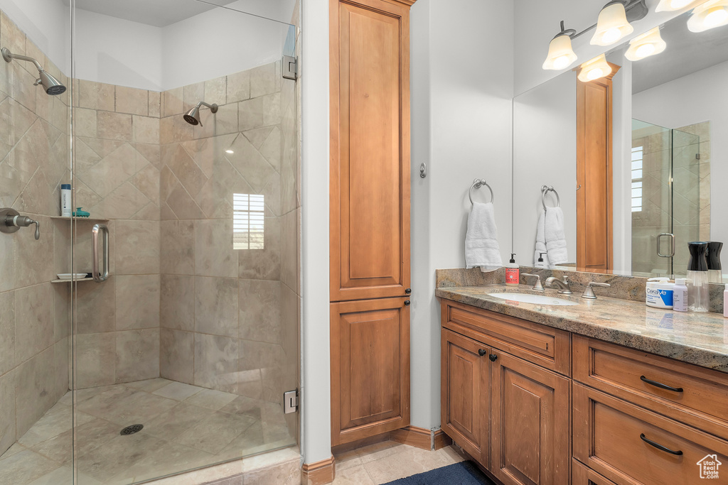 Bathroom featuring tile patterned flooring, a shower with door, and vanity