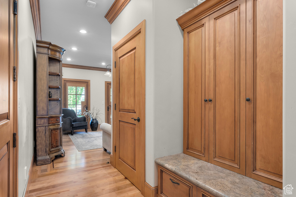 Mudroom with ornamental molding and light hardwood / wood-style flooring