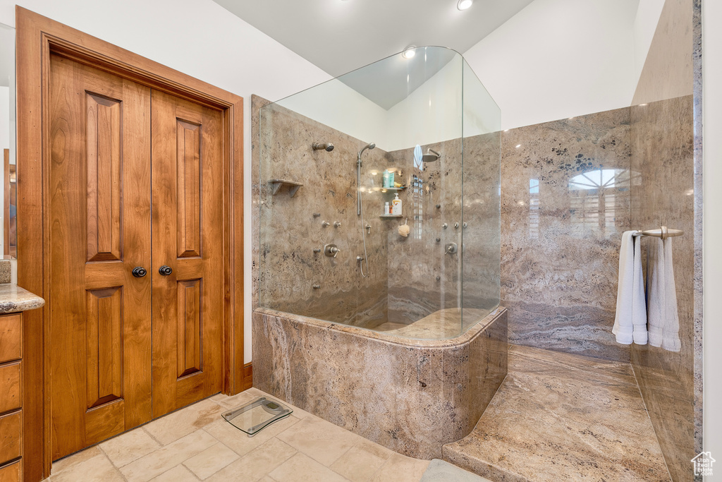 Bathroom featuring lofted ceiling, tile patterned flooring, and a tile shower