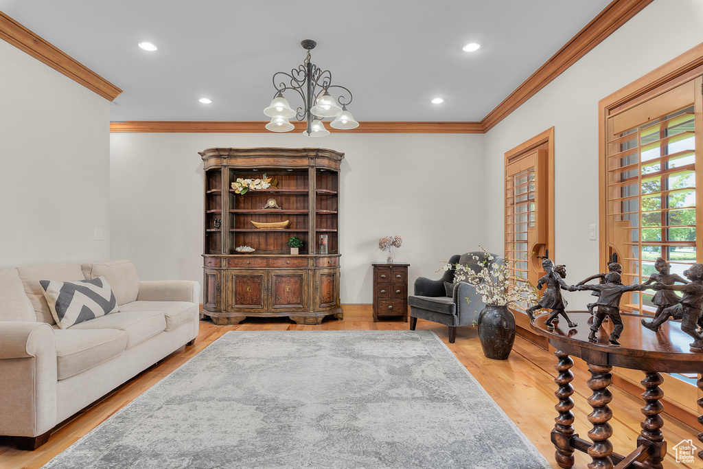 Living area with light wood-type flooring, an inviting chandelier, and crown molding