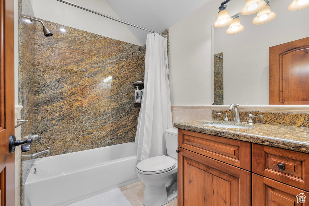 Full bathroom with tile patterned floors, shower / bath combination with curtain, toilet, and vanity