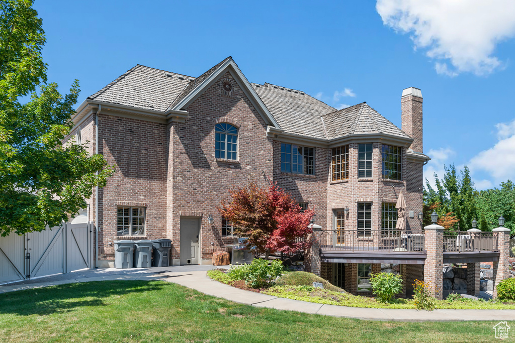 Back of property featuring a lawn and a balcony